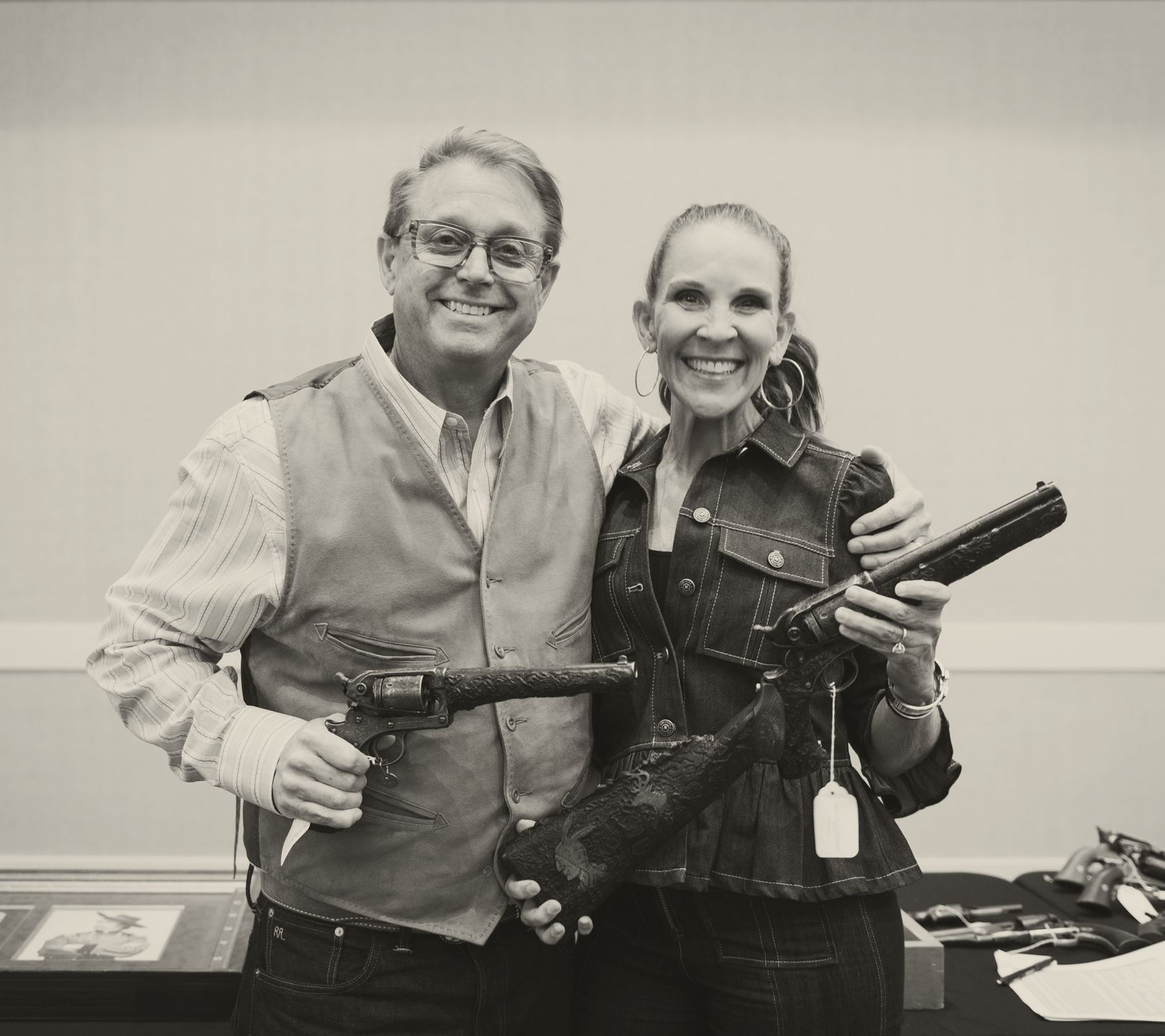 Brian and Donna Witherell smiling and holding the carved Starr revolvers, one fitted with its carved shoulder stock